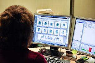 A woman analysing the digital scan of fingerprints.